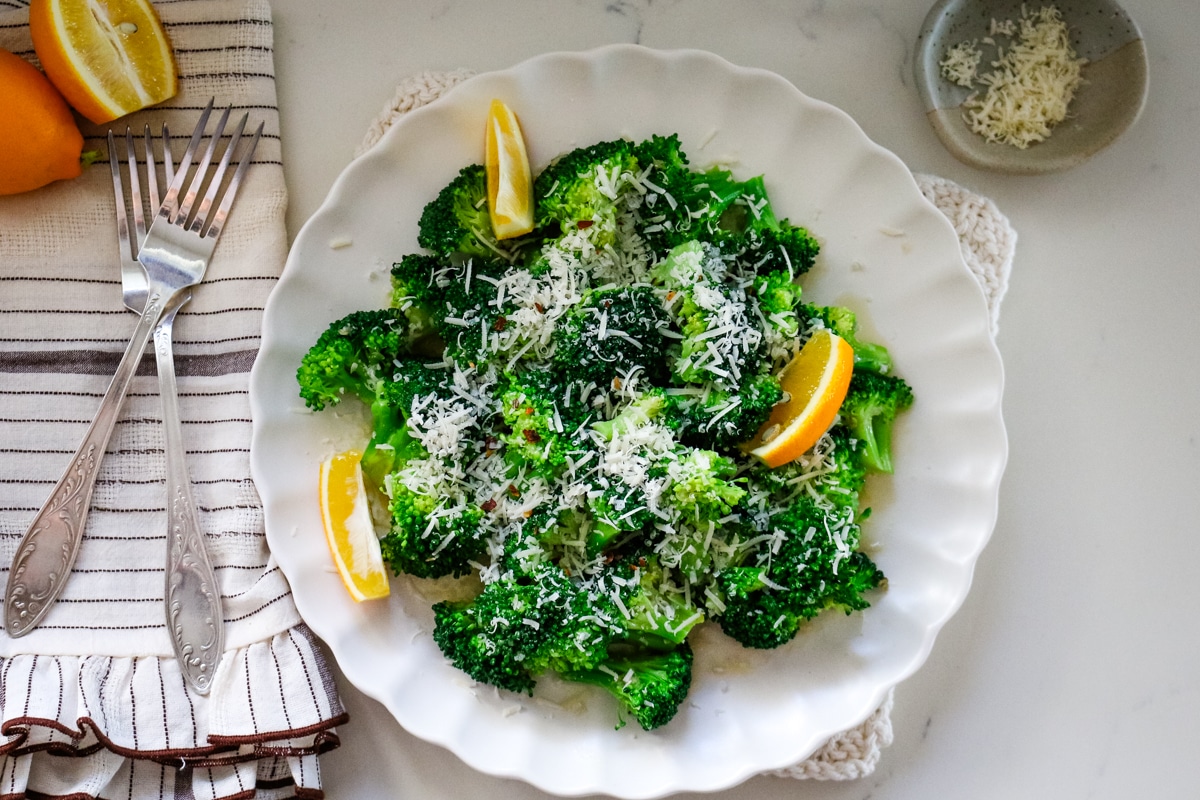 Lemon broccoli on a white plate with two forks on the side.