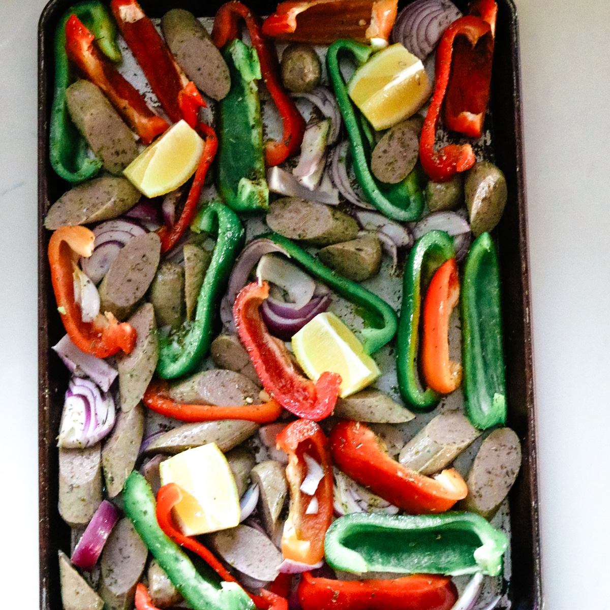 Seasoned sausage and peppers on a baking sheet.