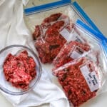 Ground beef with organ meat in a clear bowl and a freezer ziplock on the side.