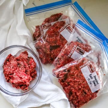 Ground beef with organ meat in a clear bowl and a freezer ziplock on the side.