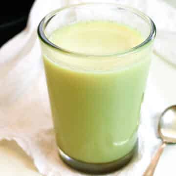 beef tallow in a glass jar with a spoon to the side.