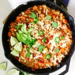 Ground beef and sweet potato in a skillet with lime and parsley beside it.