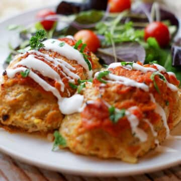 cabbage rolls on a white plate with sour cream drizzle.