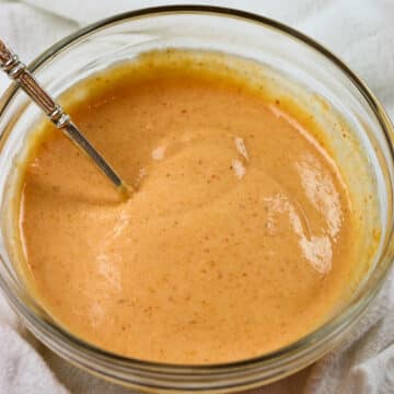 Sriracha mayo in a clear bowl, and there’s a spoon with it.