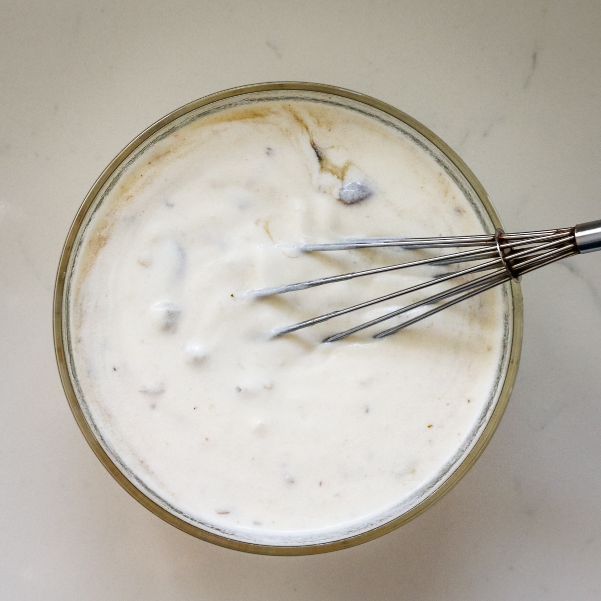 Whisking the cream in a clear bowl.