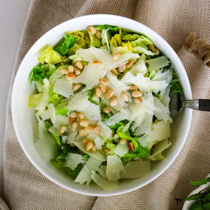 Romaine salad in a white bowl with a fork in it.
