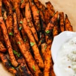 Sweet potato fries on a white plate with parchment paper.