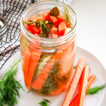 Slices of carrots on the side of an airtight jar of carrots, placed on a white plate.