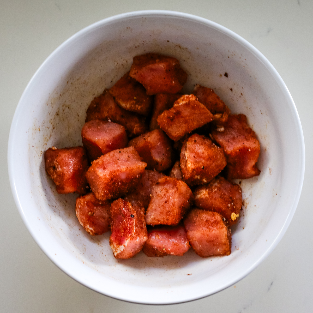 pork bites seasoned in white bowl.