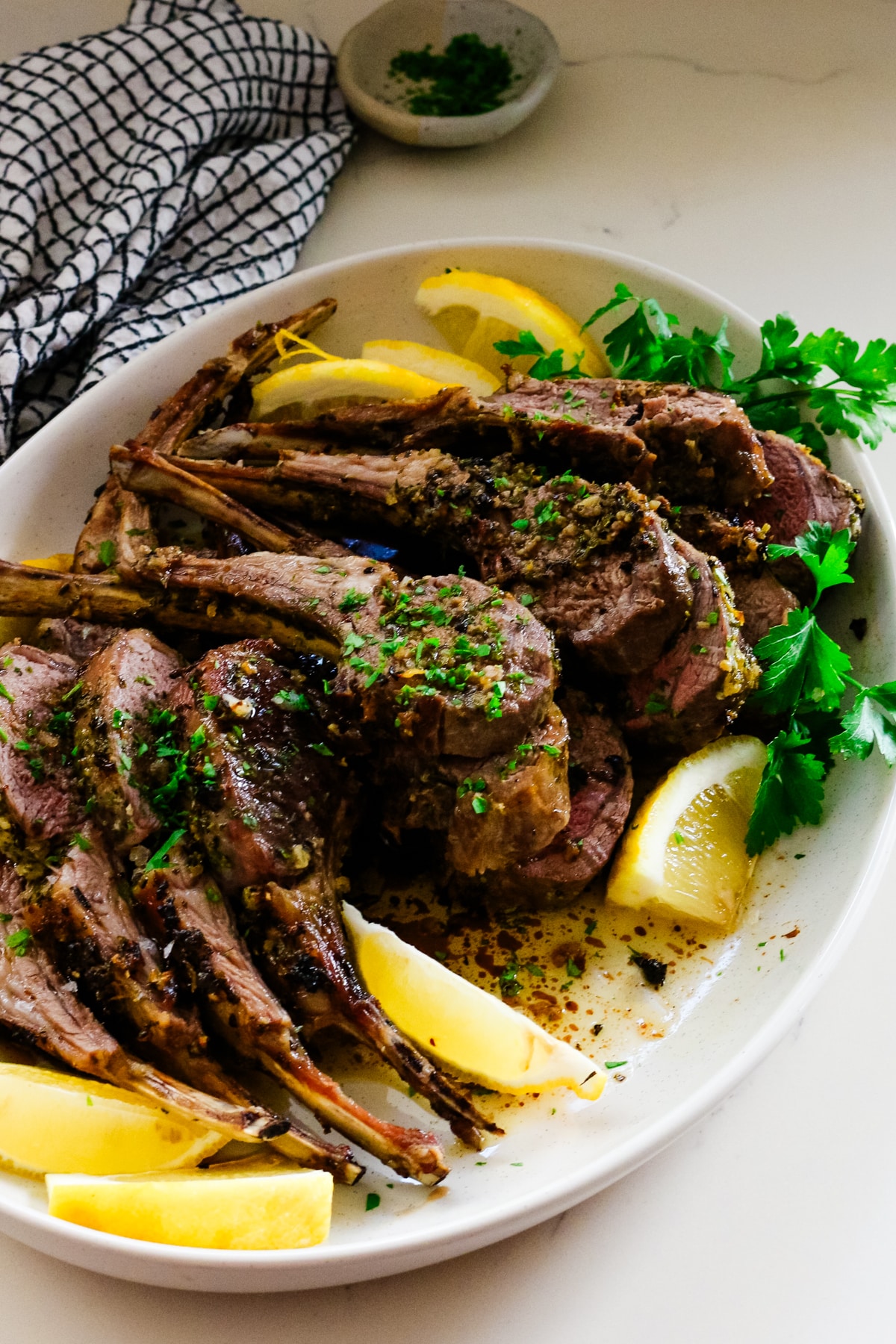 roasted rack of lamb on plate with lemon and cilantro.