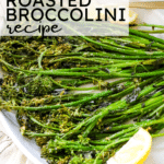 Roasted broccoli with lemon and a fork on a white platter.