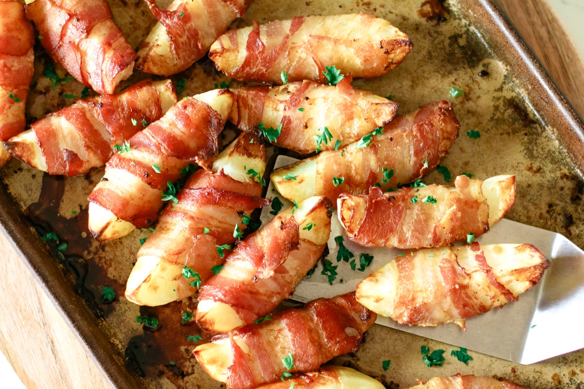 Bacon wrapped potatoes on a baking pan.