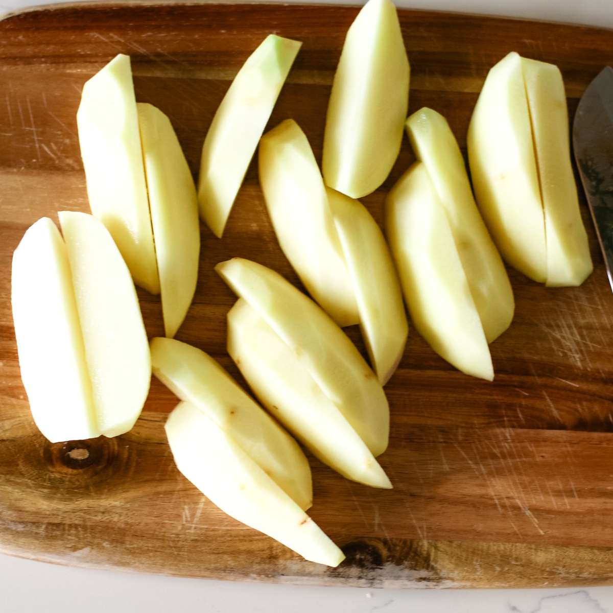 sliced potatoes on a wood cutting board.