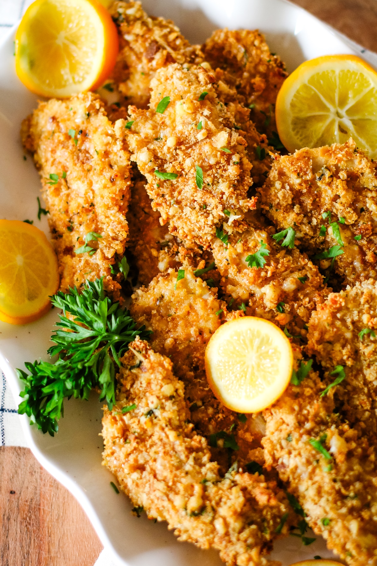 oven-baked chicken cutlets on a plate with lemon slices.
