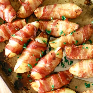 close-up of bacon wrapped potatoes on a baking pan.