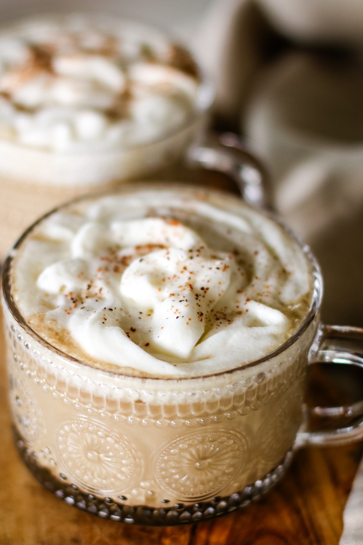 pumpkin spice latte served in a clear glass mug.