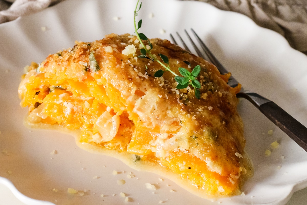 cut slice of butternut squash gratin on a plate with a fork.