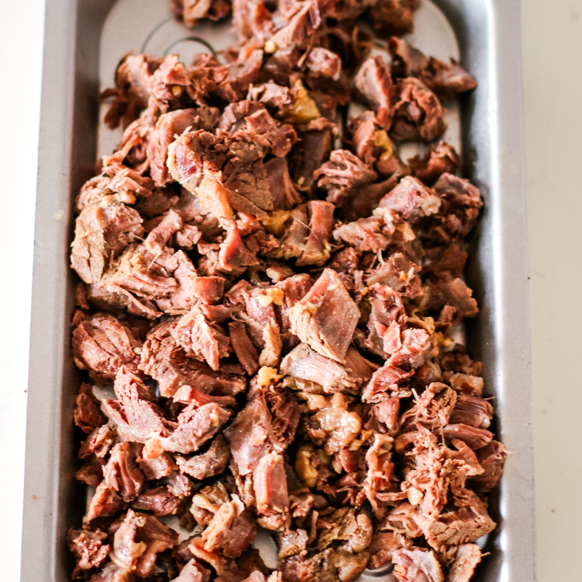 Tender, cooked beef slices arranged neatly on a tray.