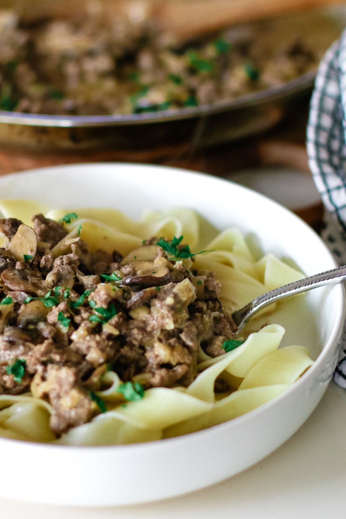 pasta with ground beef stroganoff in a small bowl topped with herbs.