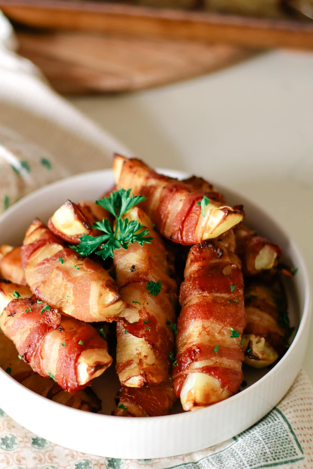 Bacon wrapped potatoes in a dish on a kitchen towel.