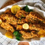 oven-baked chicken cutlets on a plate with lemon slices.
