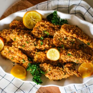 oven-baked chicken cutlets on a plate with lemon slices.