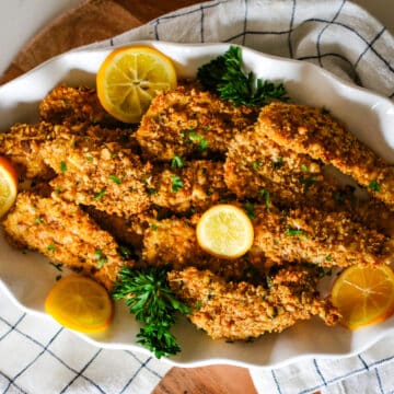 oven-baked chicken cutlets on a plate with lemon slices.