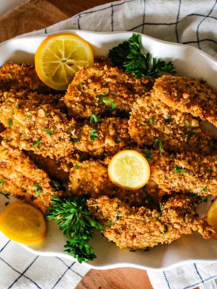 oven-baked chicken cutlets on a plate with lemon slices.