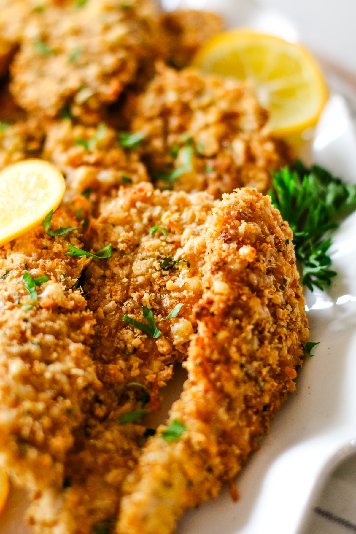 oven-baked chicken cutlets on a plate with lemon slices.