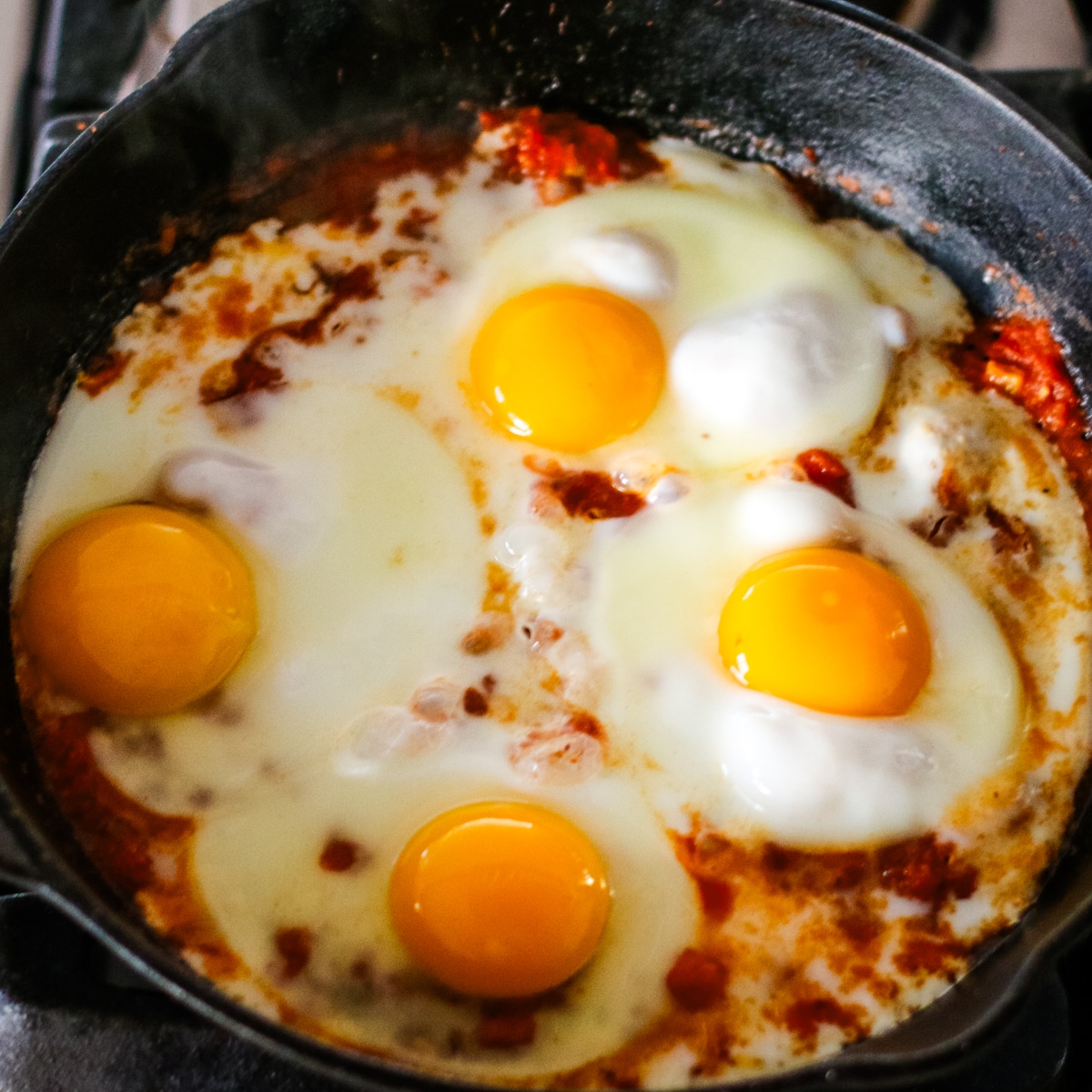 pizza sauce with an egg on a pan.
