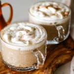 two pumpkin spice latte served in a coffee glass.