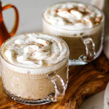 two pumpkin spice latte served in a coffee glass.