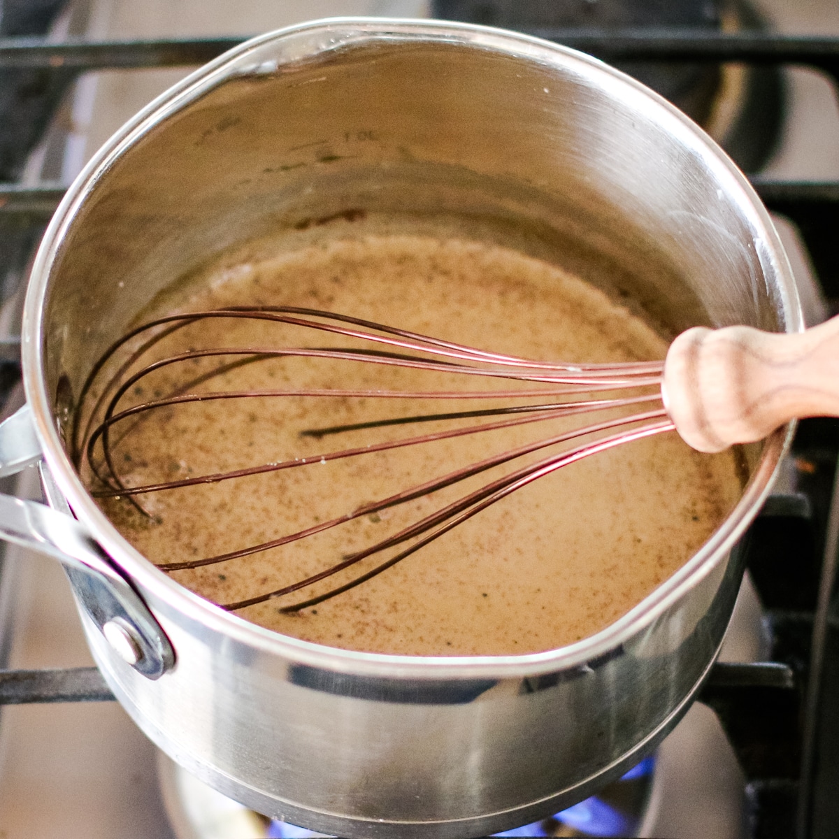 ingredients being whisked in a small saucepan with a whisk.