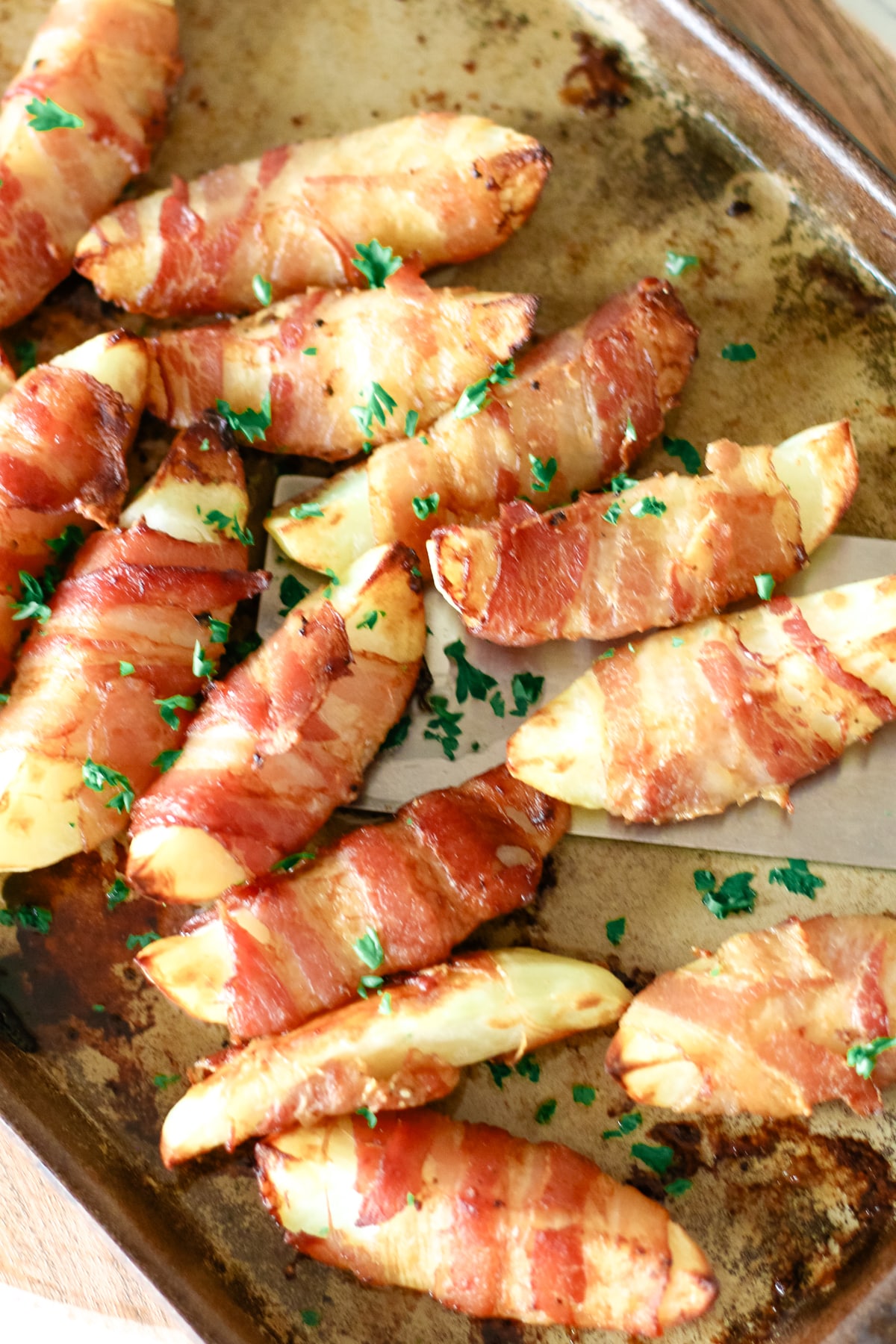 cooked bacon wrapped potatoes on a baking pan.