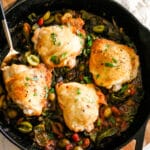 basque chicken in a skillet with a serving spoon.