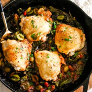 basque chicken in a skillet with a serving spoon.
