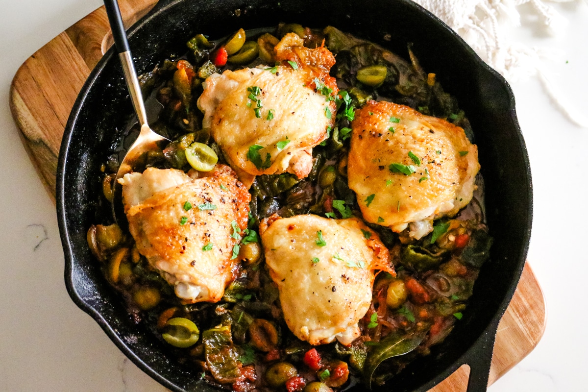 basque chicken in a skillet with a serving spoon.