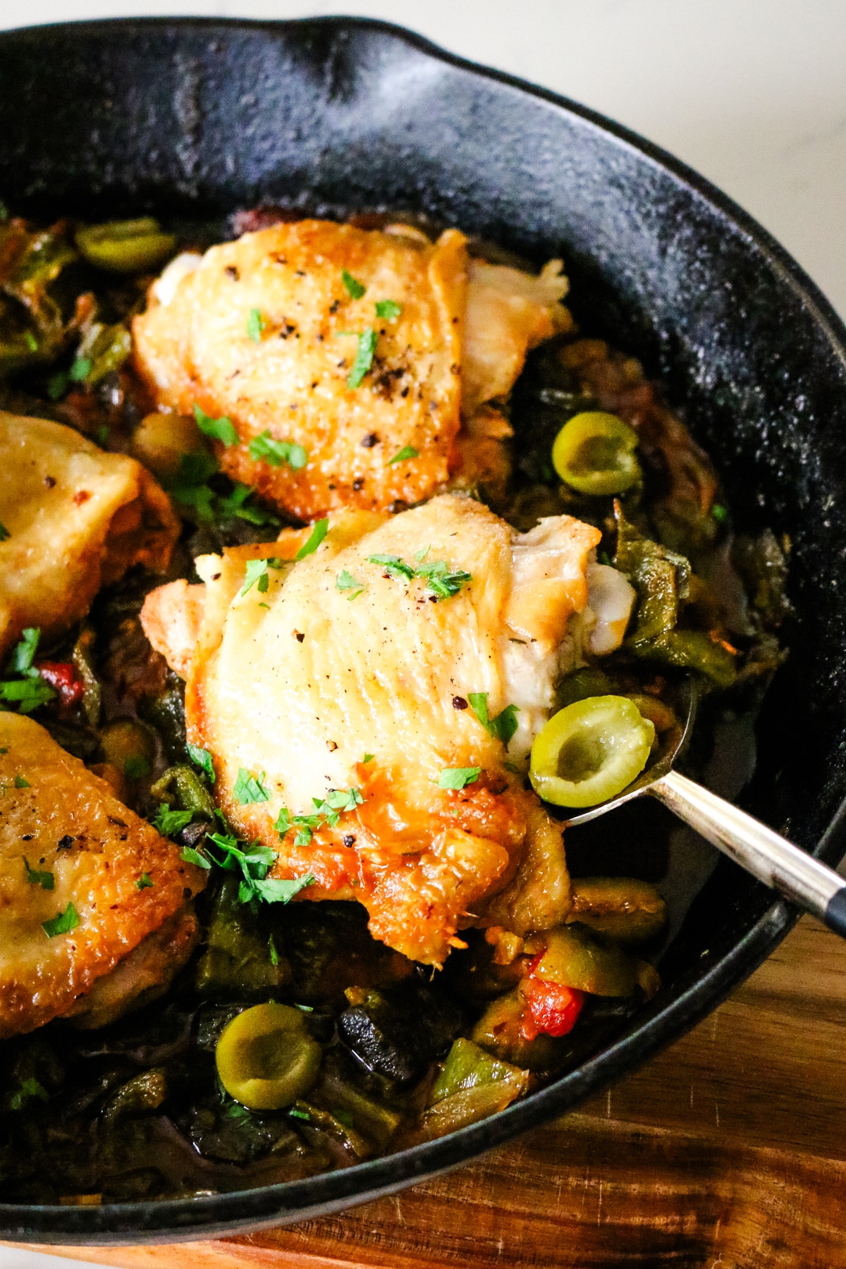 basque chicken in a skillet with a serving spoon.