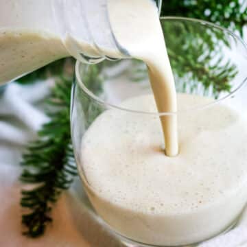 eggnog poured into a glass from a glass bottle.
