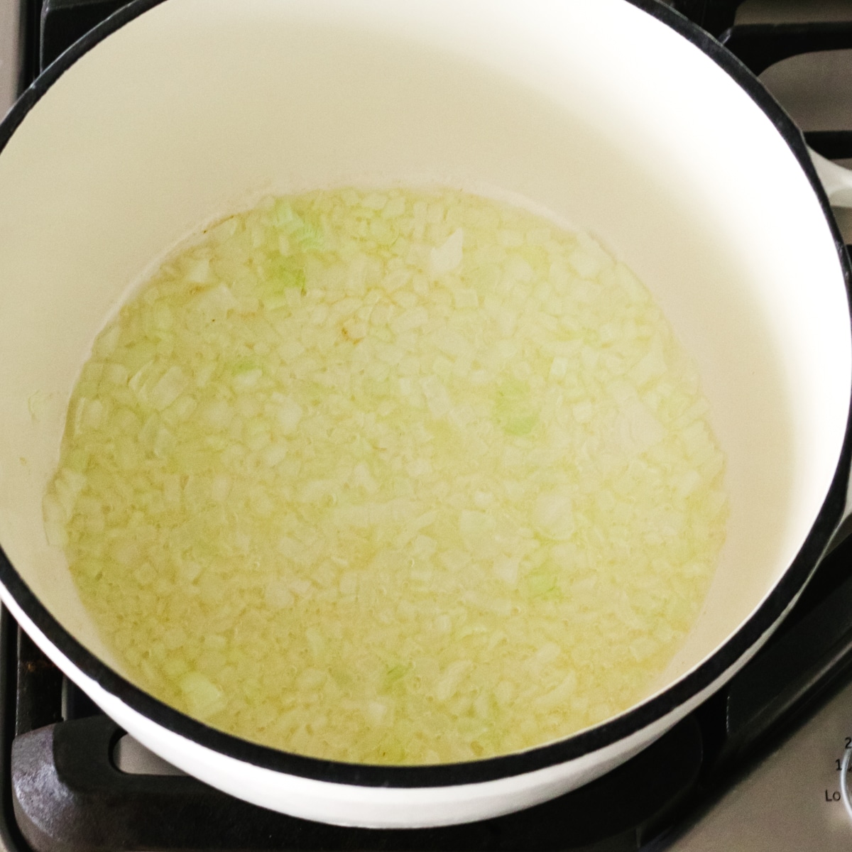 sautéing chopped onions in a pot.