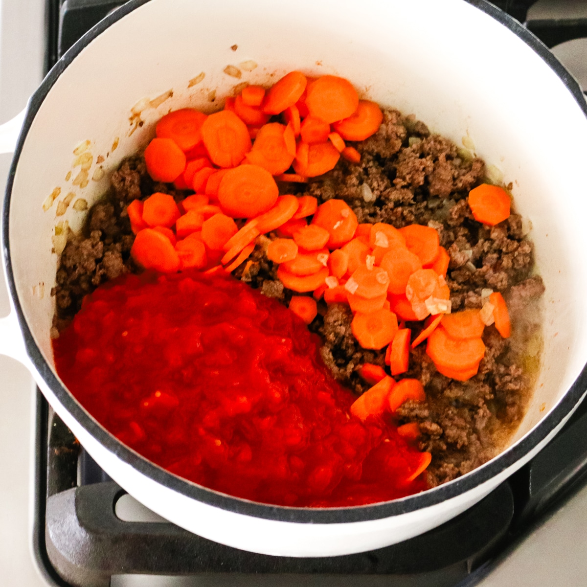 cooked ground beef with sliced carrots and tomato sauce in a pot.