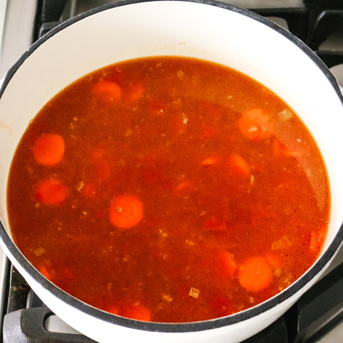 ground beef and vegetable soup simmering in a pot.