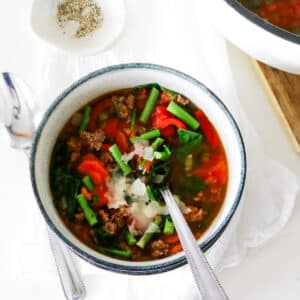ground beef and vegetable soup served in a bowl with a spoon.