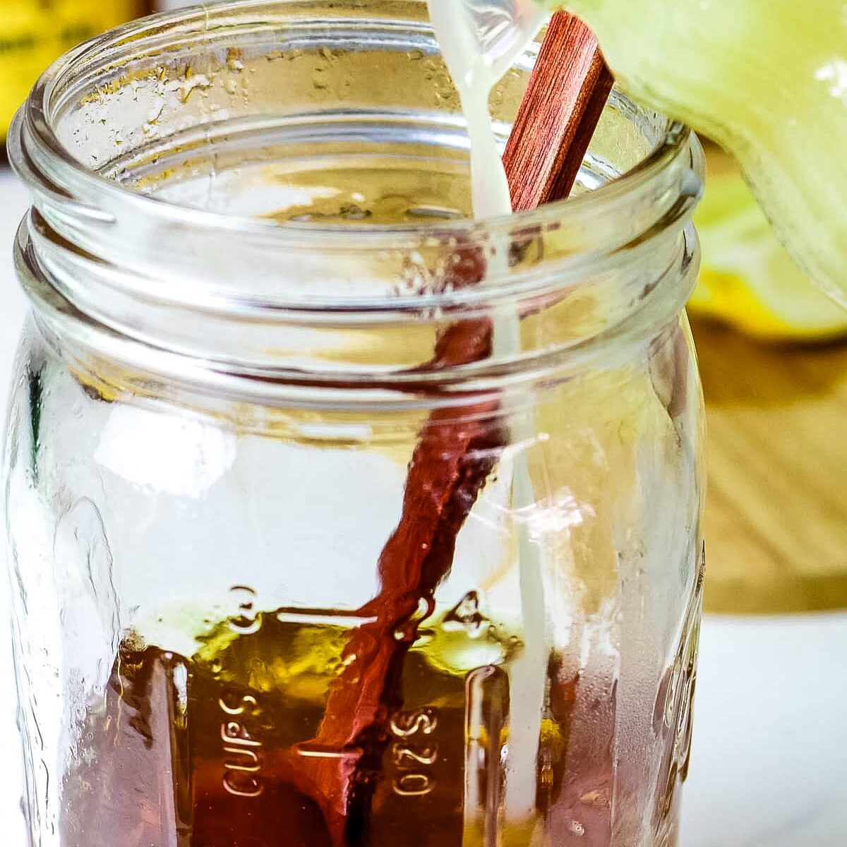 honey juice is added to brewed herbal tea in a mason jar.