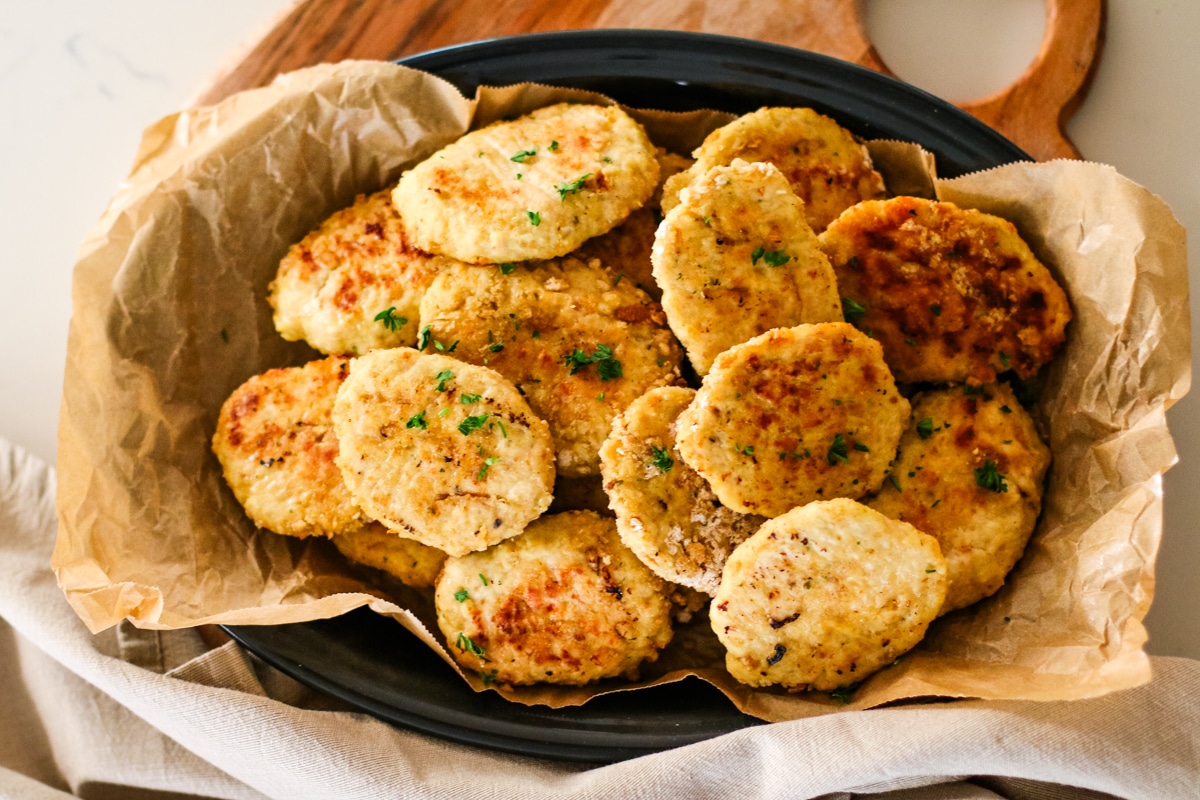 a platter piled high with golden-brown chicken kotleti, garnished with chopped parsley.