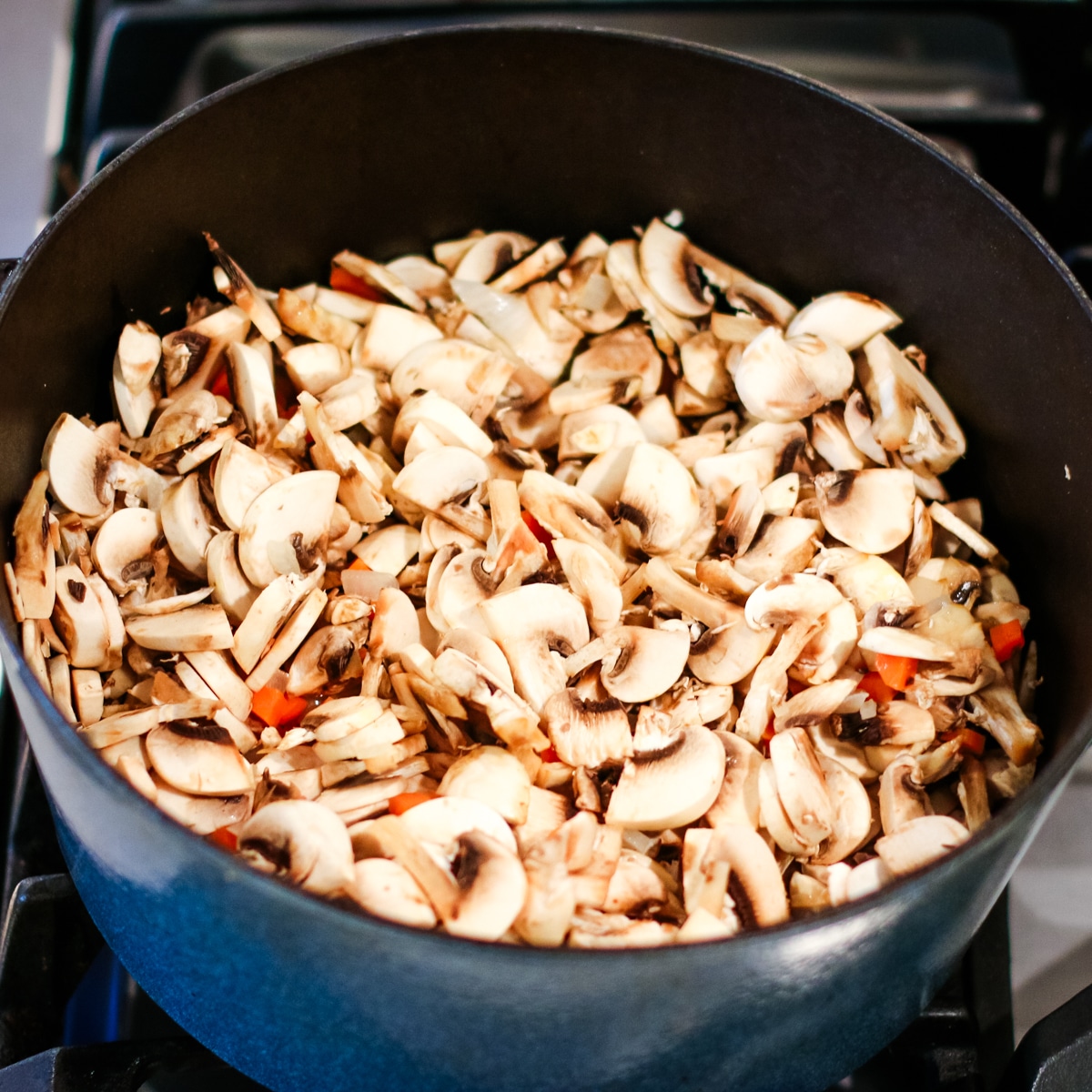 Diced mushrooms and carrots in a pot.
