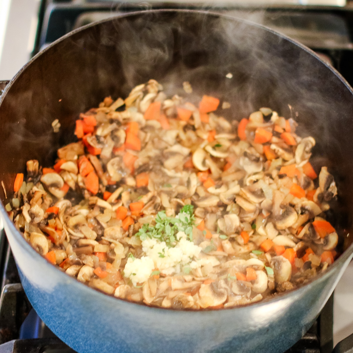 Diced onion, mushrroms, and carrots sauted in a pot.