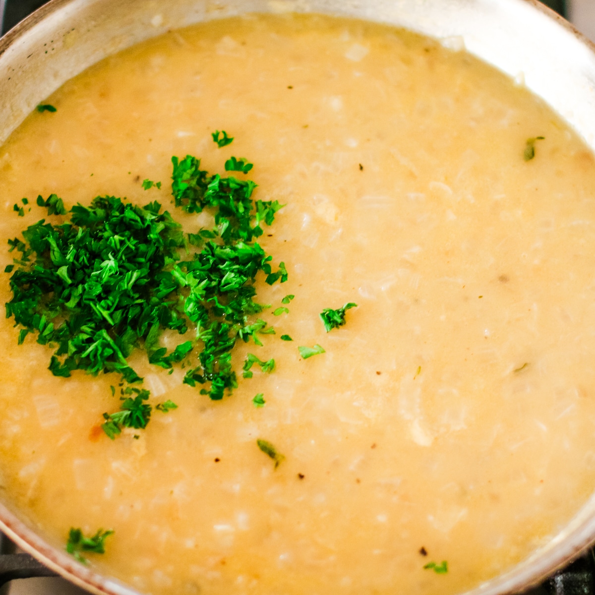 pan of light brown onion gravy or sauce, topped with fresh, chopped parsley.