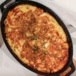 baked delicata squash gratin in a baking dish, topped with melted cheese and breadcrumbs, golden.