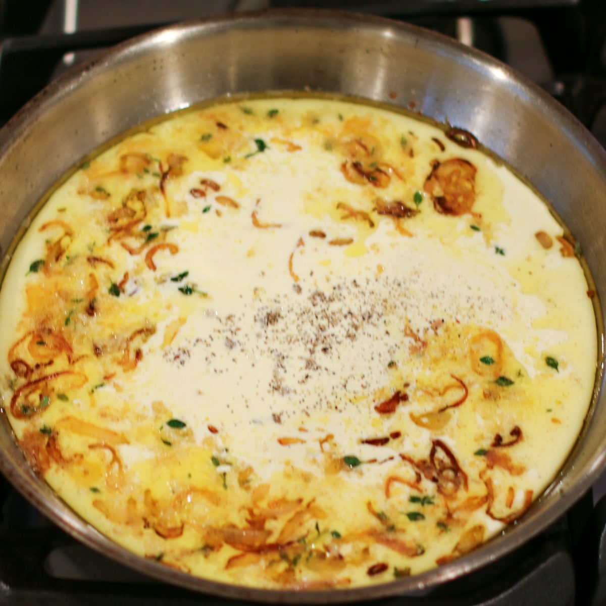 heavy cream added to a pan over medium-low heat, being stirred and gently simmered until slightly thickened.